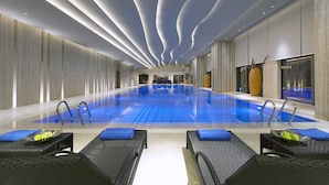 Une piscine intérieure moderne, dotée de chaises longues et offrant une vue dégagée sur l’ensemble de l’espace piscine.