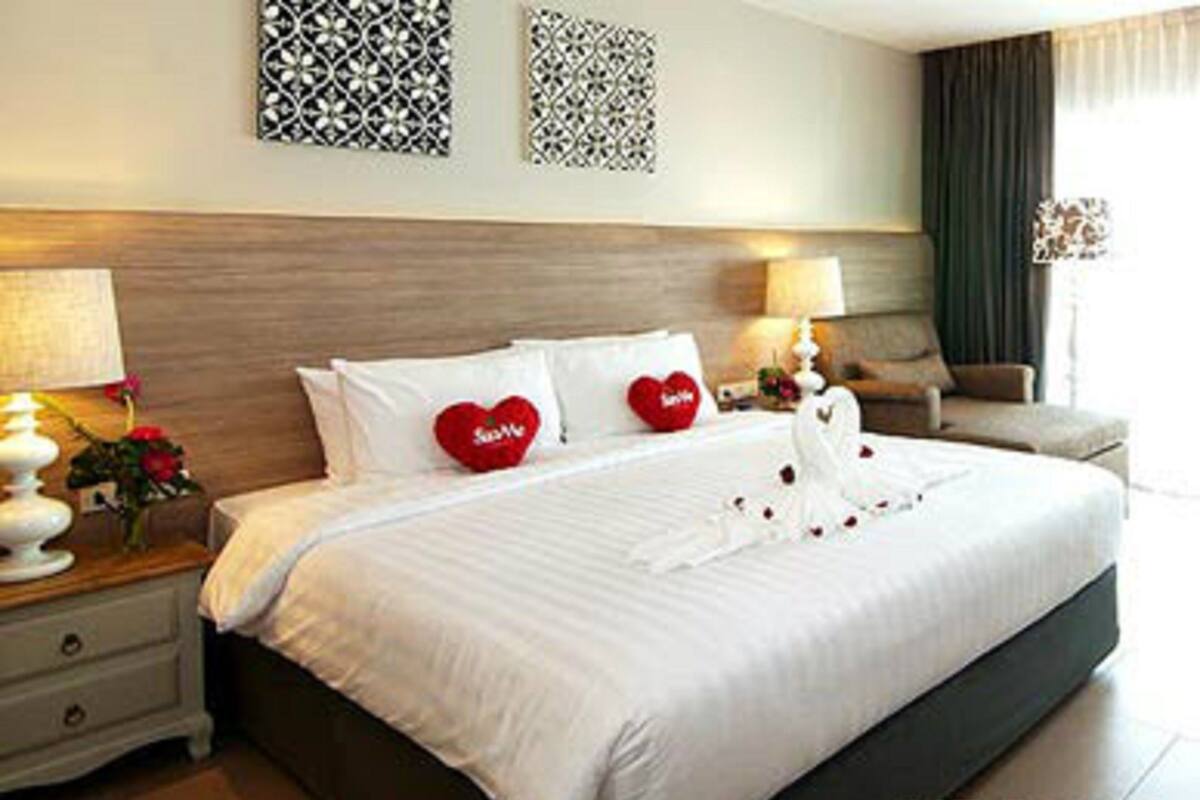 Une chambre d’hôtel avec un grand lit, deux tables de chevet, une chaise et des œuvres d’art décoratives au mur.