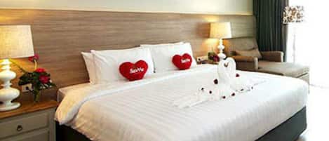 A hotel room with a large bed, two bedside tables, a chair, and decorative wall art.