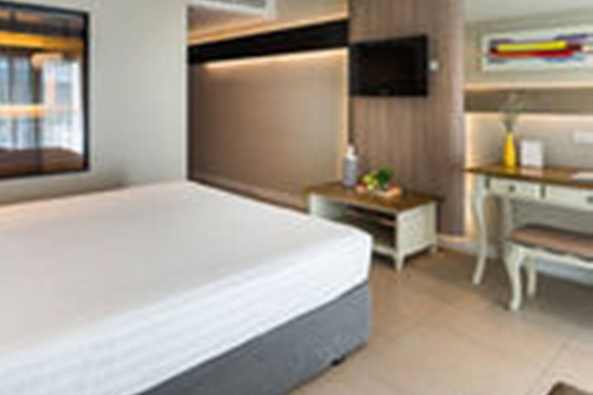Une chambre d’hôtel moderne équipée d’un grand lit, d’un bureau, d’une chaise et d’un téléviseur.