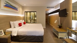A modern hotel room with a large bed, a desk, a TV, and a window with blinds. - Sea Me Spring Too Hotel (Pattaya)