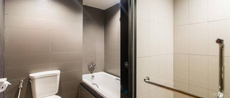 A modern bathroom with a toilet, bathtub, and a glass shower enclosure.