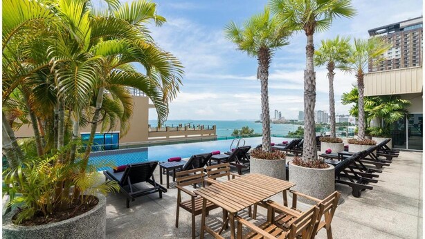 A rooftop pool area with lounge chairs, tables, and potted plants. - Sea Me Spring Too Hotel (Pattaya)