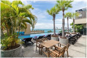 A rooftop pool area with lounge chairs, tables, and potted plants. - Sea Me Spring Too Hotel (Pattaya)