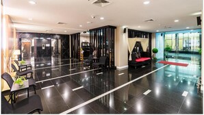 A modern lobby with a black marble reception desk, seating area with chairs, and a red sofa. - Sea Me Spring Too Hotel (Pattaya)