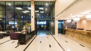 A spacious lobby with a reception desk, a seating area with a purple sofa, and a large glass wall with a television screen. - Sea Me Spring Hotel (Pattaya)