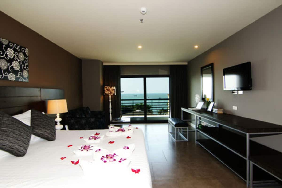 A hotel room with a bed, a desk, a TV, and a balcony with a view.