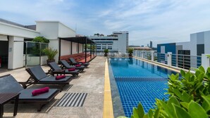 A rooftop pool area with lounge chairs and a clear view of the city skyline. - Sea Me Spring Hotel (Pattaya)