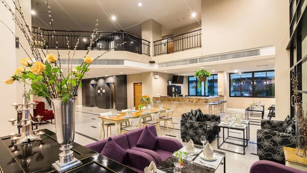 A spacious, multi-level hotel lobby with a dining area, seating arrangements, and a balcony. - Sea Me Spring Hotel (Pattaya)
