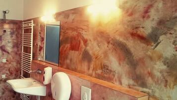 A bathroom with a wooden vanity, a sink, a towel rack, and a mirror.