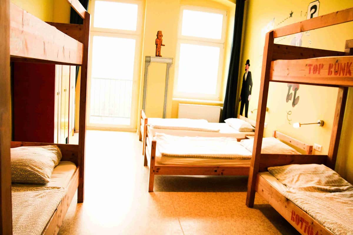 Un dormitorio con literas, una mesita pequeña y una ventana.