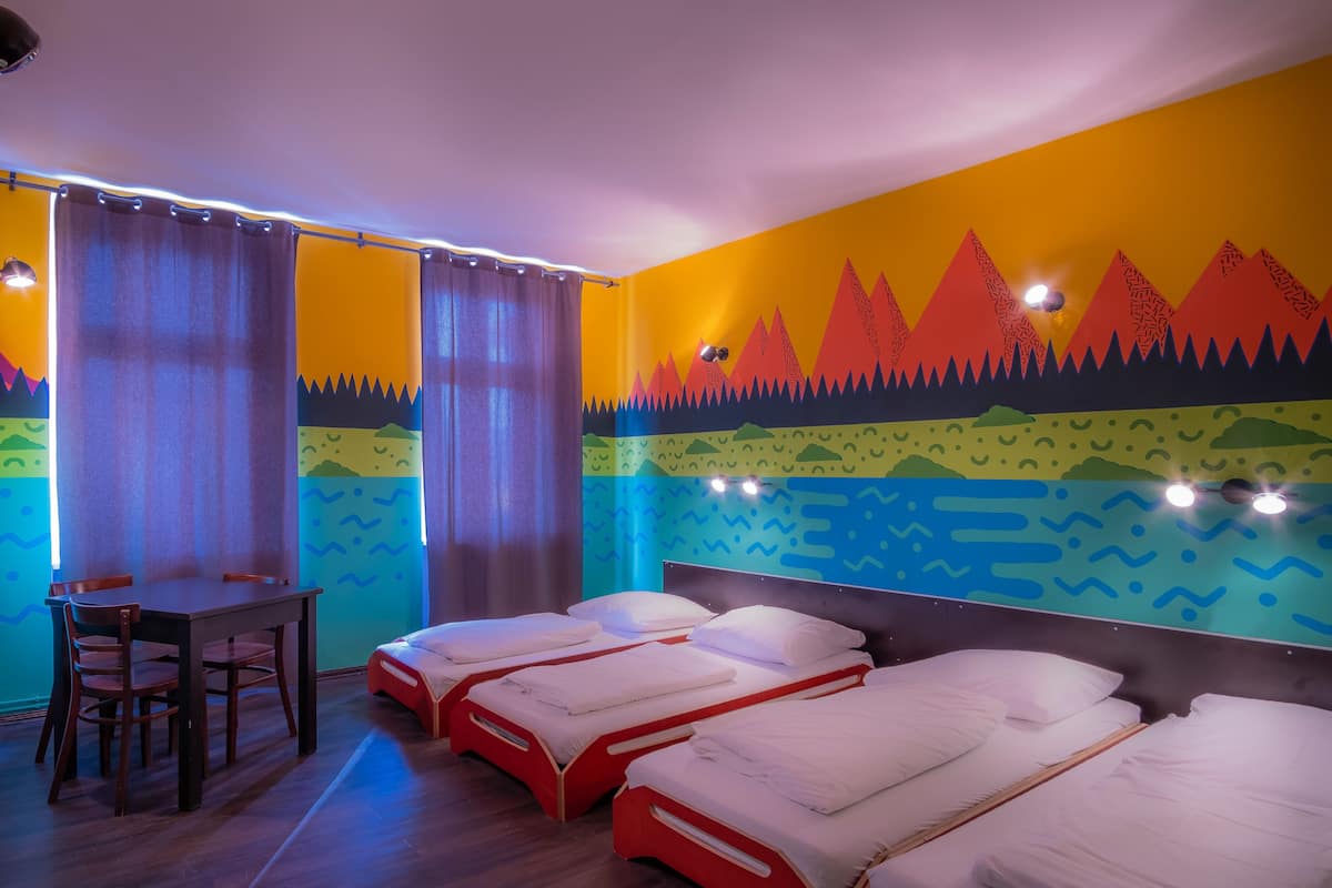 Habitación de hotel con tres camas individuales, un escritorio de madera y una silla.
