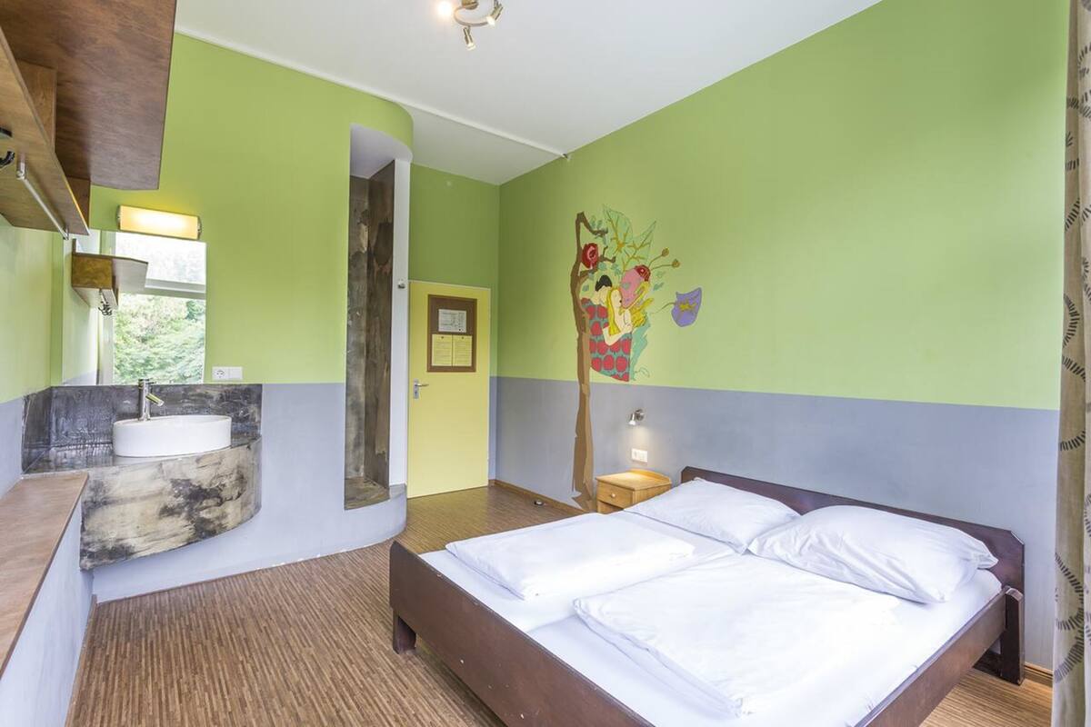 Habitación de hotel con cama, lavamanos y espejo.