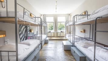 Um quarto de dormitório com beliches, escrivaninha e cadeira.