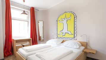 Ein modernes Hotelzimmer mit einem hölzernen Bett, weißen Leinen, einem Schreibtisch und einem großen Spiegel.