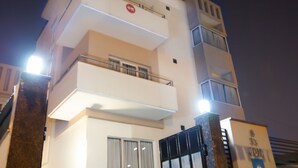 A multi-story building with a gated entrance, potted plants, and a balcony on the second floor. - OYO Rooms Cyber City (Gurugram)