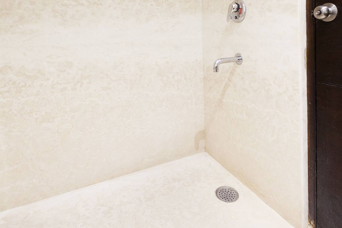 A corner of a bathroom with a shower, a toilet, and a sink.