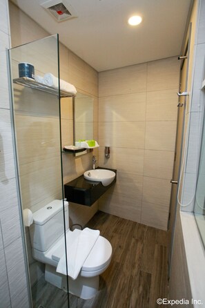 A modern bathroom with a glass partition, a white toilet, a sink, and a shower area. - J8 Hotel (Singapore)