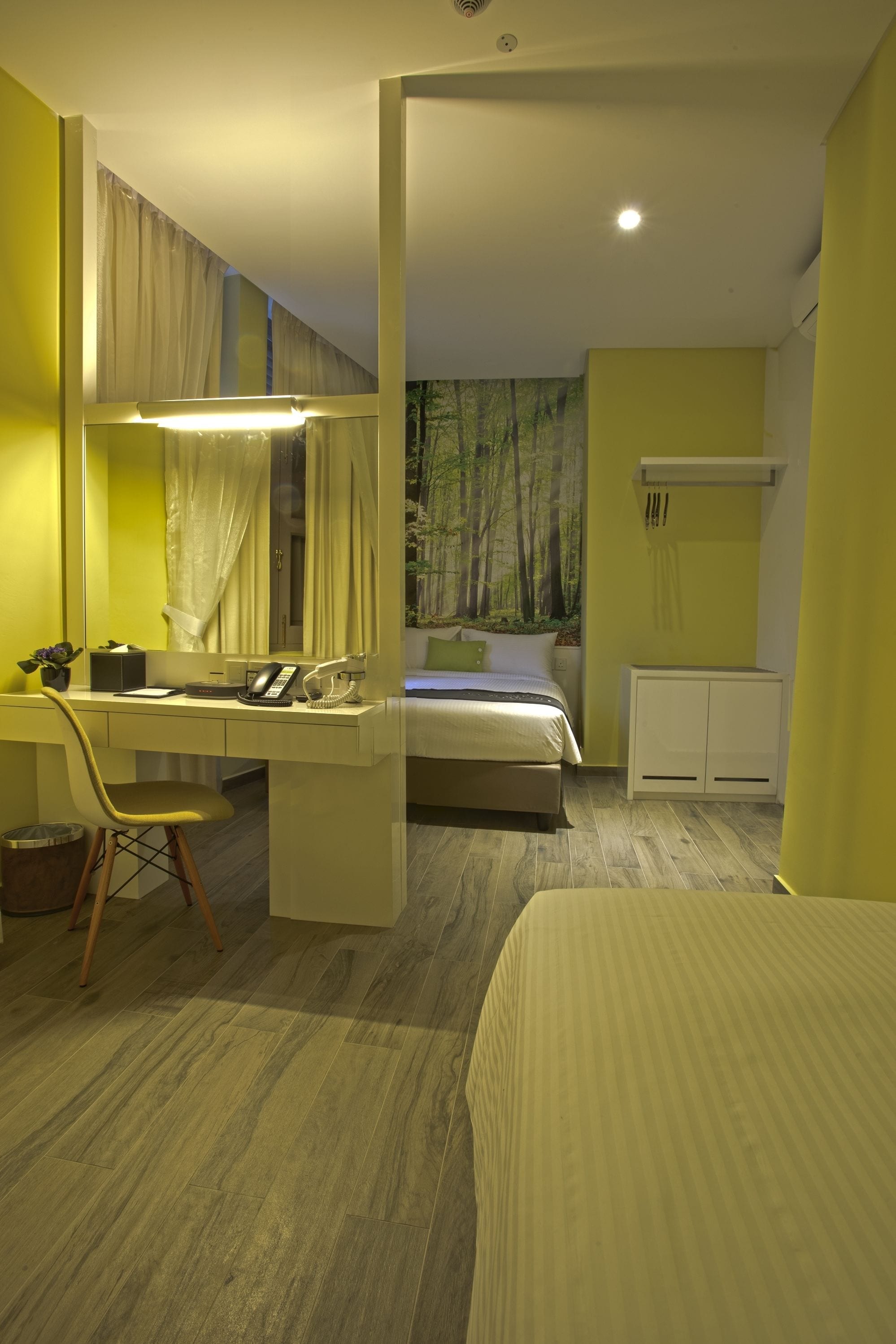 A bedroom with a bed, a desk with a chair, a mirror, and a wardrobe.