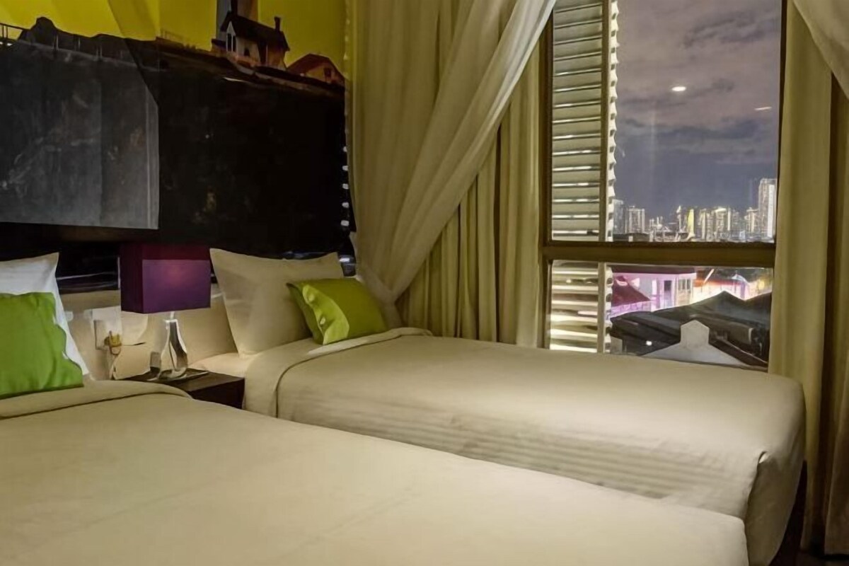 A hotel room with two beds, a window with a city view, and a bunk bed above.