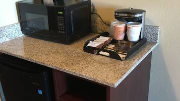 A kitchen counter with a coffee maker, microwave, and coffee pods.