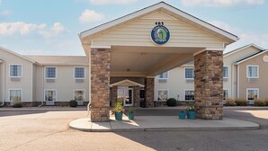 A hotel entrance with a covered porch, stone pillars, and a Cobblestone Lounge sign. - Cobblestone Inn & Suites - Eaton (Eaton)