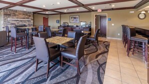 A hotel lobby with a stone wall, multiple seating areas, a kitchen, and a clock on the wall. - Cobblestone Inn & Suites - Eaton (Eaton)