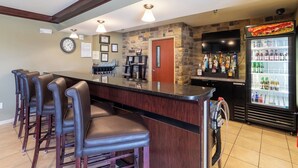 A bar area with a stone wall, a clock, and a refrigerator stocked with beverages. - Cobblestone Inn & Suites - Eaton (Eaton)