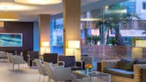 A modern lobby with a seating area, a reception desk, and a large window overlooking a cityscape. - Astral Nirvana Suites (Eilat)