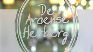 Un logotipo con el texto 'De Arcense Herberg'.
