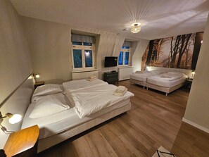 A bedroom with two beds, a television, and a large window with curtains. - Hotel Arcense Herberg (Arcen)
