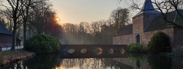 A canal with a bridge, trees, and a building with a tower. - Hotel Arcense Herberg (Arcen)