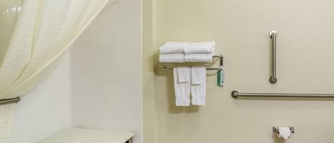 A bathroom with a shower, a toilet, a grab bar, and a towel rack.