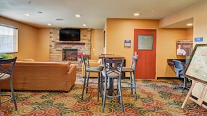 Una habitación de hotel con chimenea, un sofá, una mesa de comedor con sillas y un televisor montado en la pared.