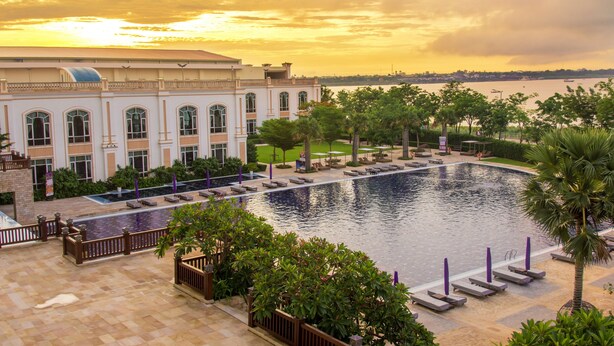 Un hotel con una piscina grande, palmeras y vistas al agua.