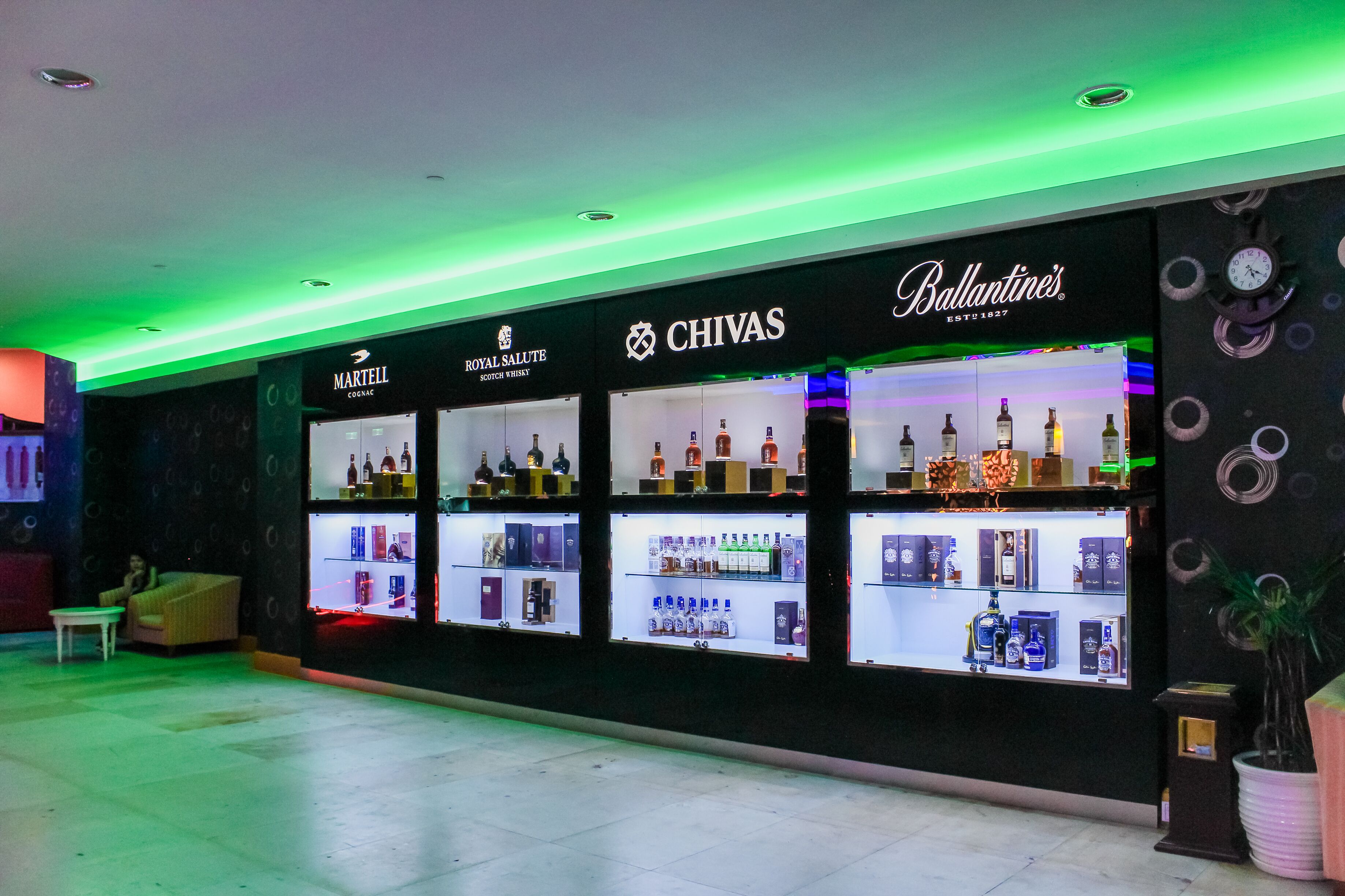 Una licorería con estantes llenos de bebidas alcohólicas y un reloj en la pared.