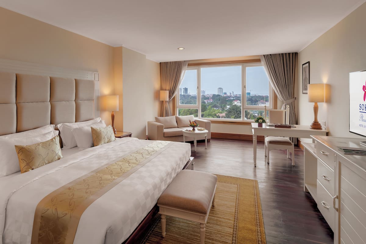 Habitación de hotel con una cama grande, un escritorio, una silla y vistas a la ciudad.
