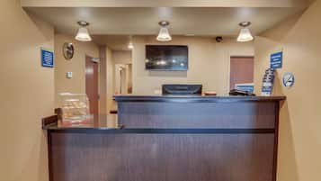 A reception desk with a ViewSonic monitor, a clock, and a sign indicating check-in times.