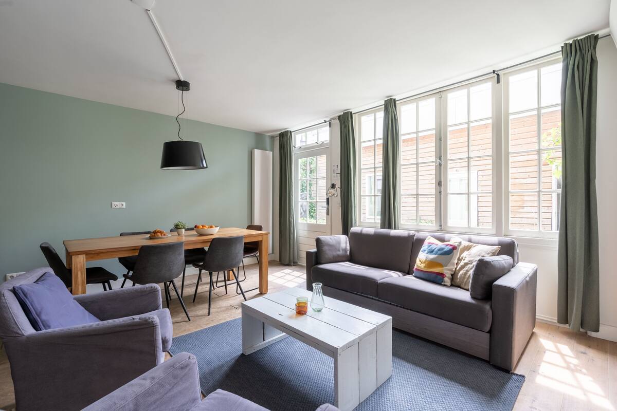 A living room with a sofa, chairs, a coffee table, and a dining table.