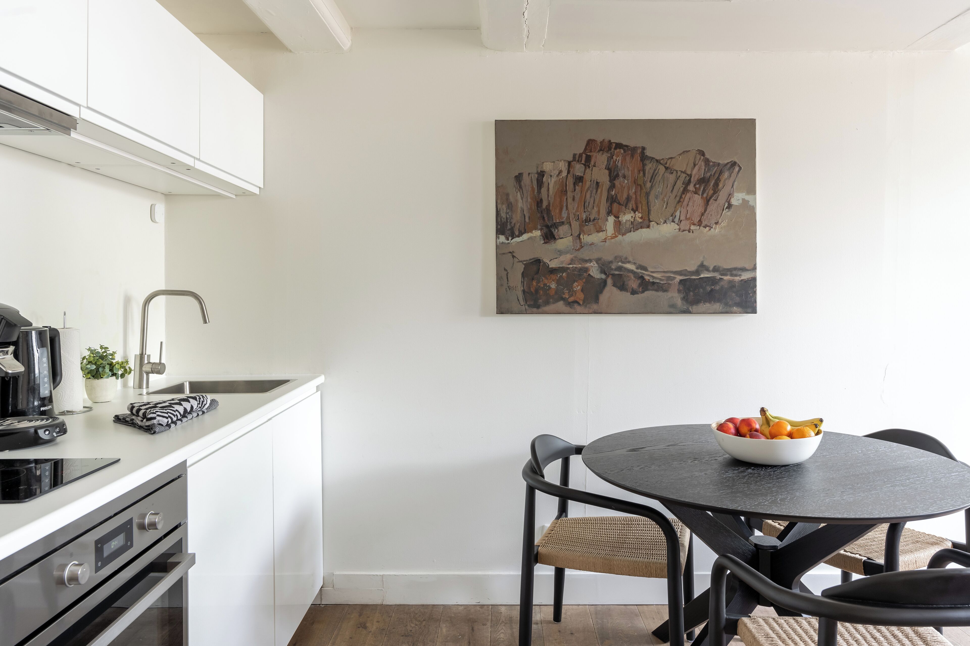A modern kitchen with white cabinets, a black countertop, and a dining area with a round table and chairs.