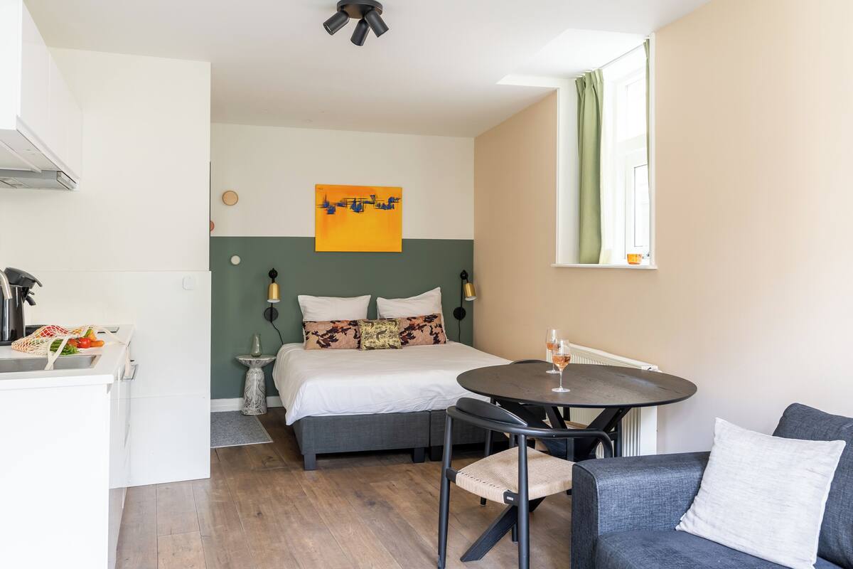 A modern bedroom with a bed, bedside table, and a small round table with chairs.