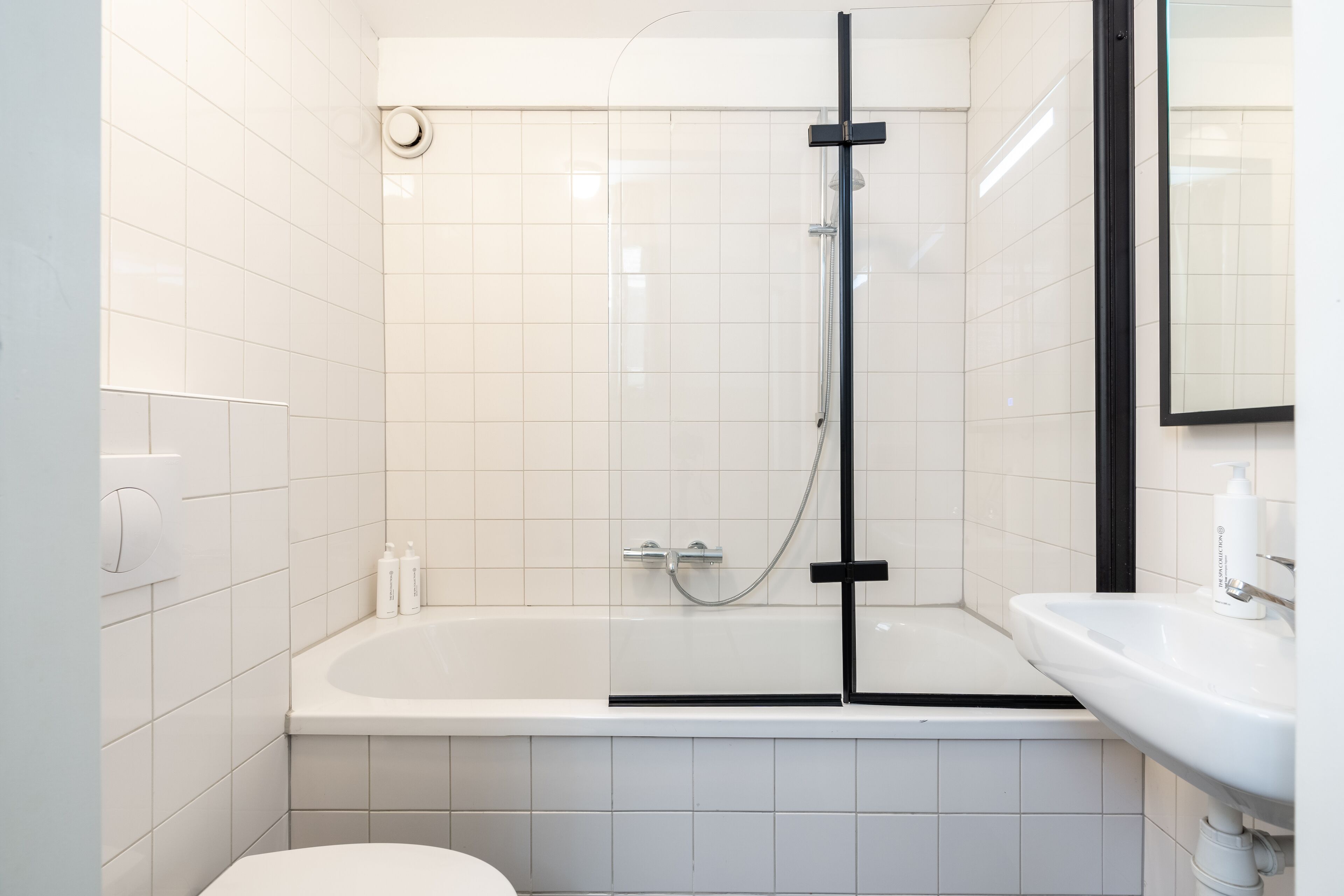 A modern bathroom with a white tiled shower enclosure, a bathtub, and a sink.