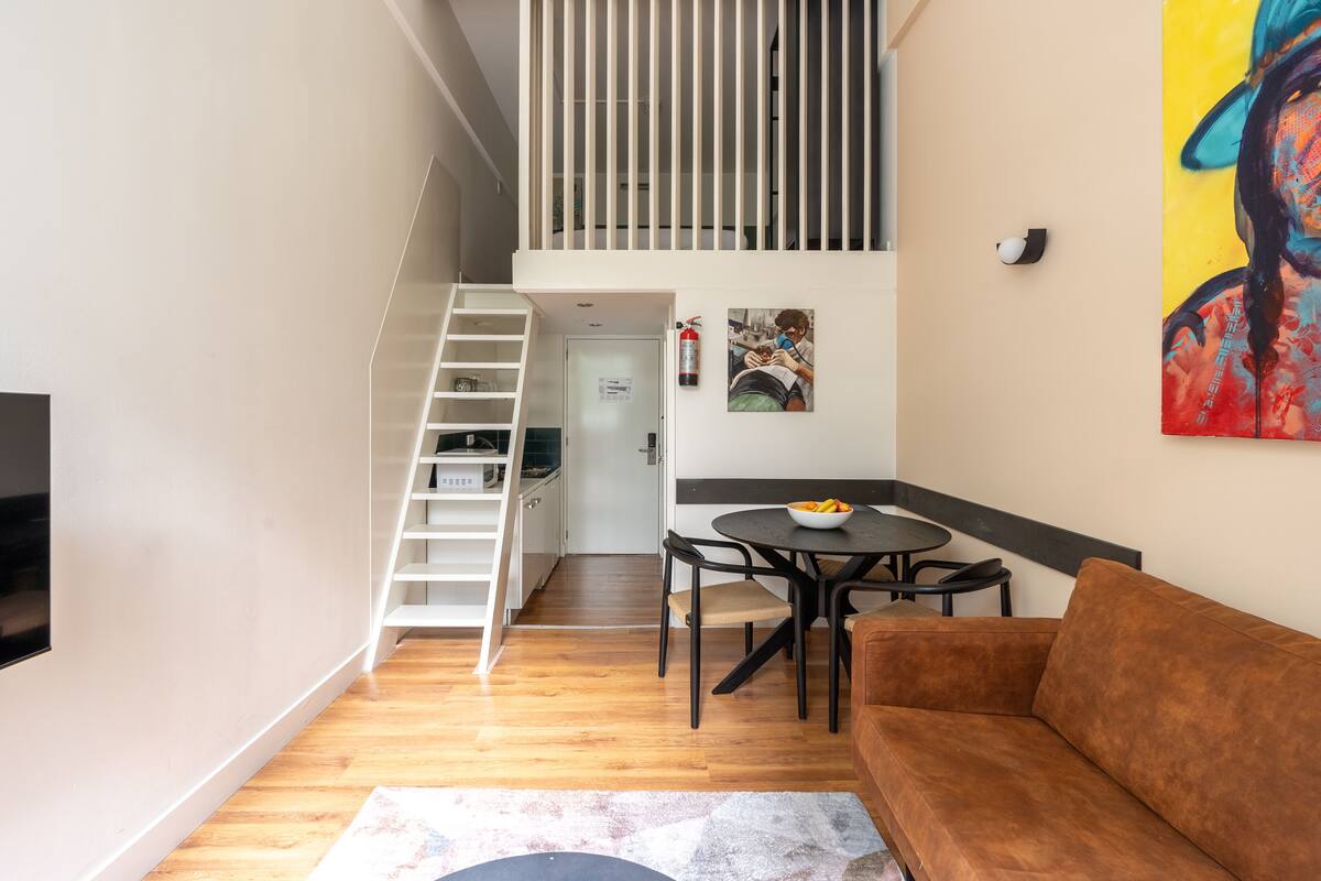 A modern living space with a staircase, a dining area, and a sofa.