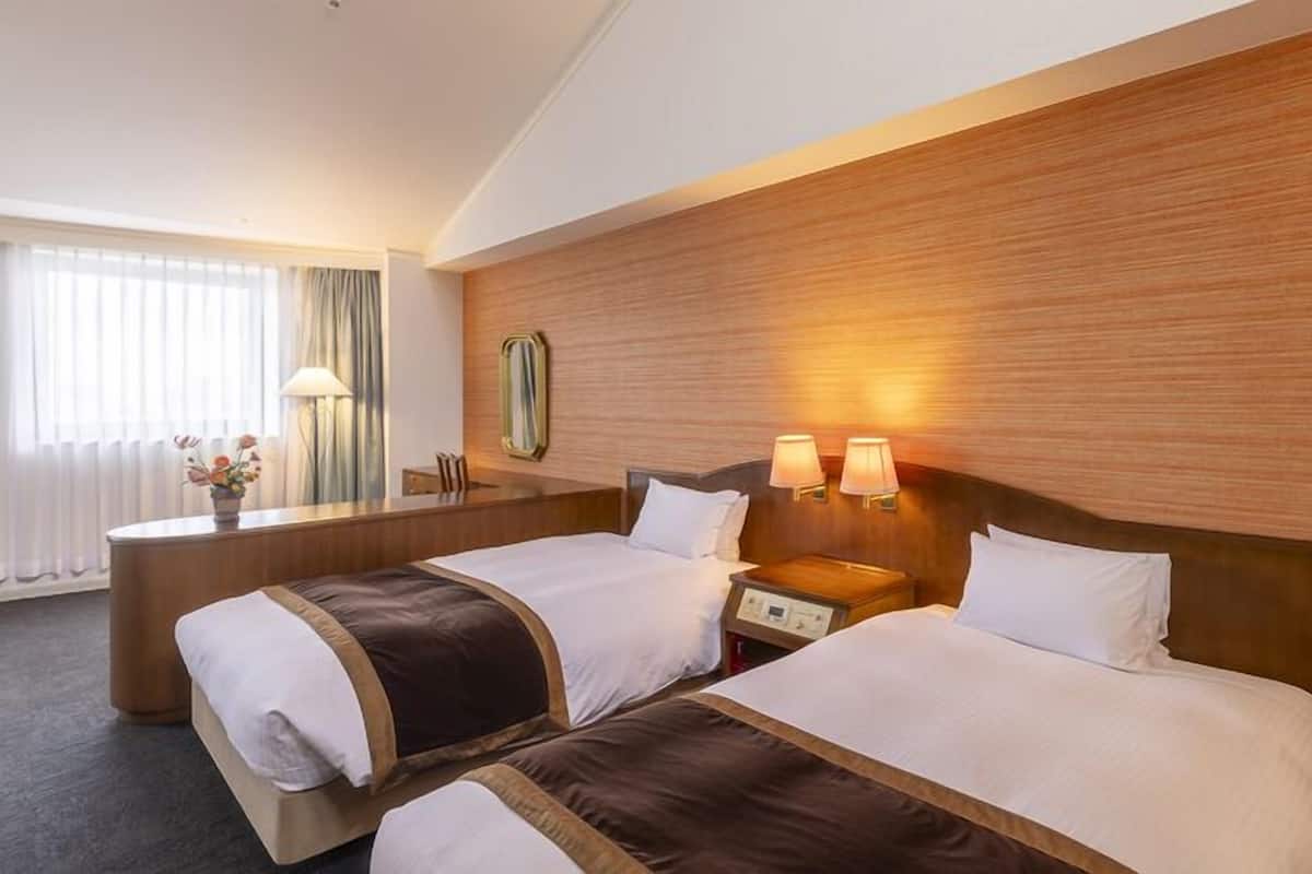 Ein Hotelzimmer mit zwei Betten, einem Schreibtisch und einem Spiegel.