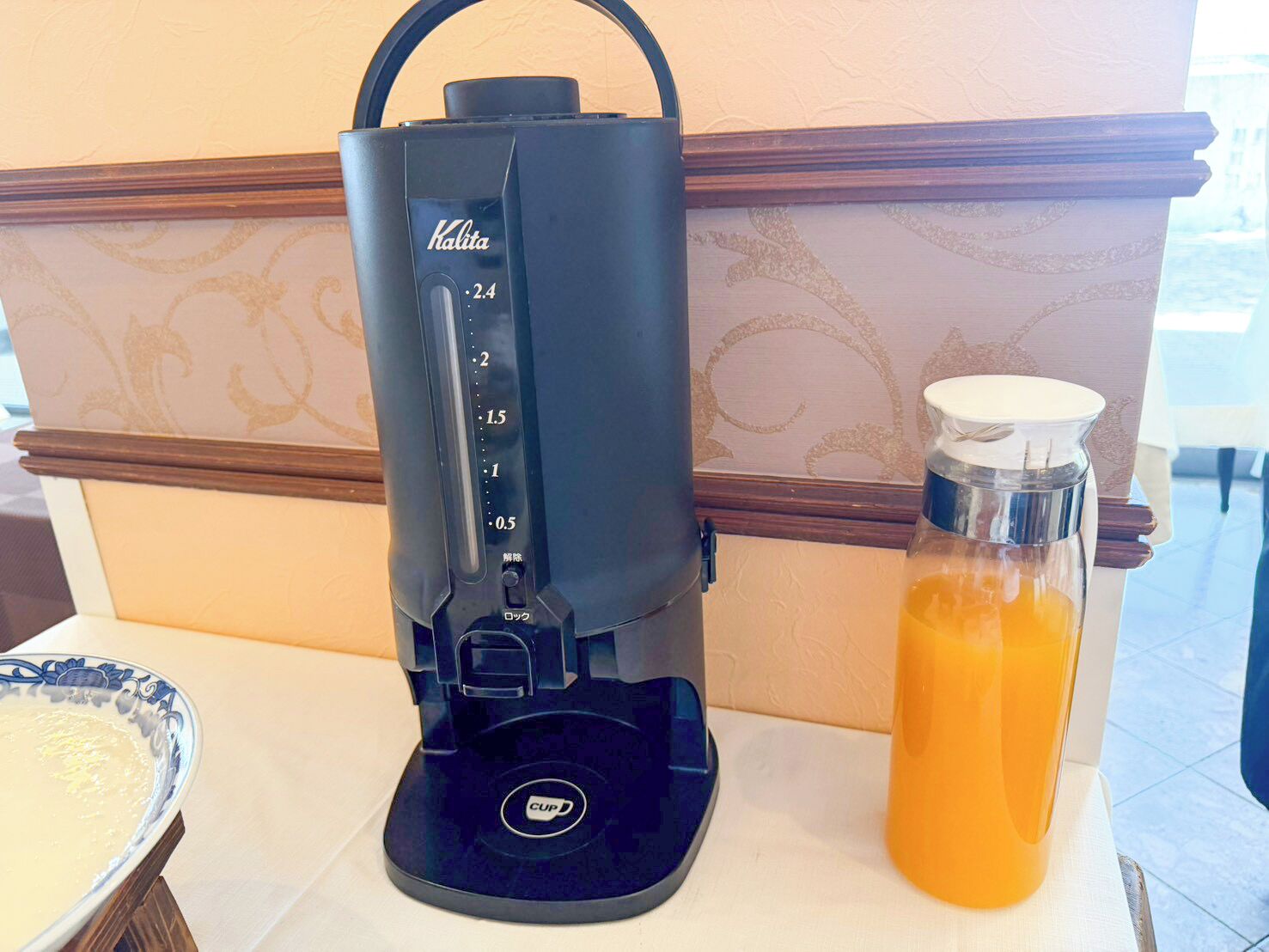 A coffee maker with a digital display and a glass carafe filled with orange juice.