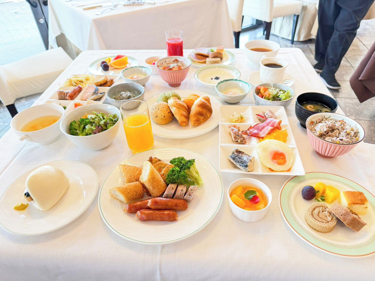 A breakfast buffet with various dishes, including bread, sausages, eggs, and fruit.