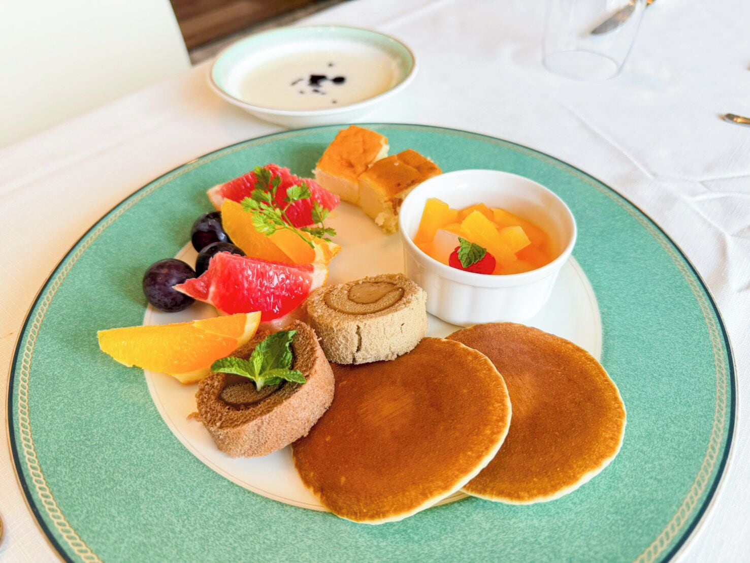 Une assiette de crêpes, une part de gâteau et un saladier de salade de fruits.