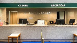 A hotel reception desk with a 'CASHIER' and 'RECEPTION' sign, a computer, and a telephone.