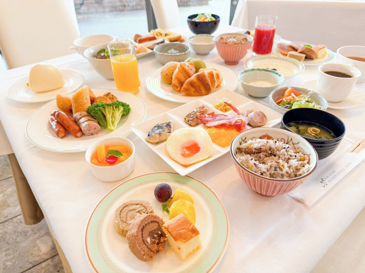Un bufé de desayuno con diversos platos, como huevos, salchichas y bollería.