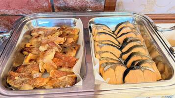 Ein Buffet mit zwei Speisenplatten, eine mit Aufschnitt und die andere mit Fisch.